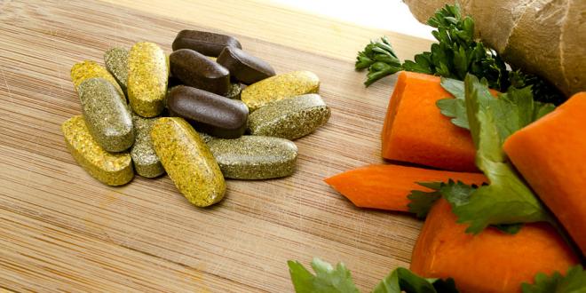 Vitamins and carrots on cutting board