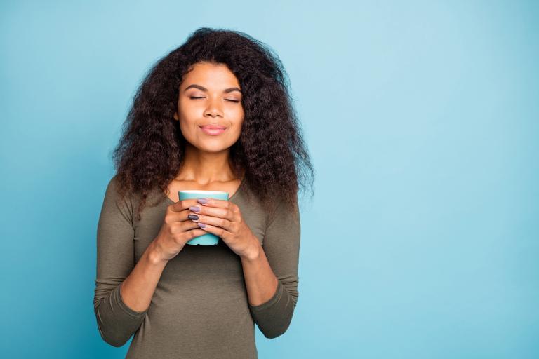 a woman with a calmly glowing smile holding a mug of tea