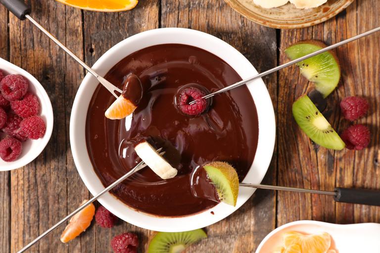 fruit getting dipped in a bowl of chocolate